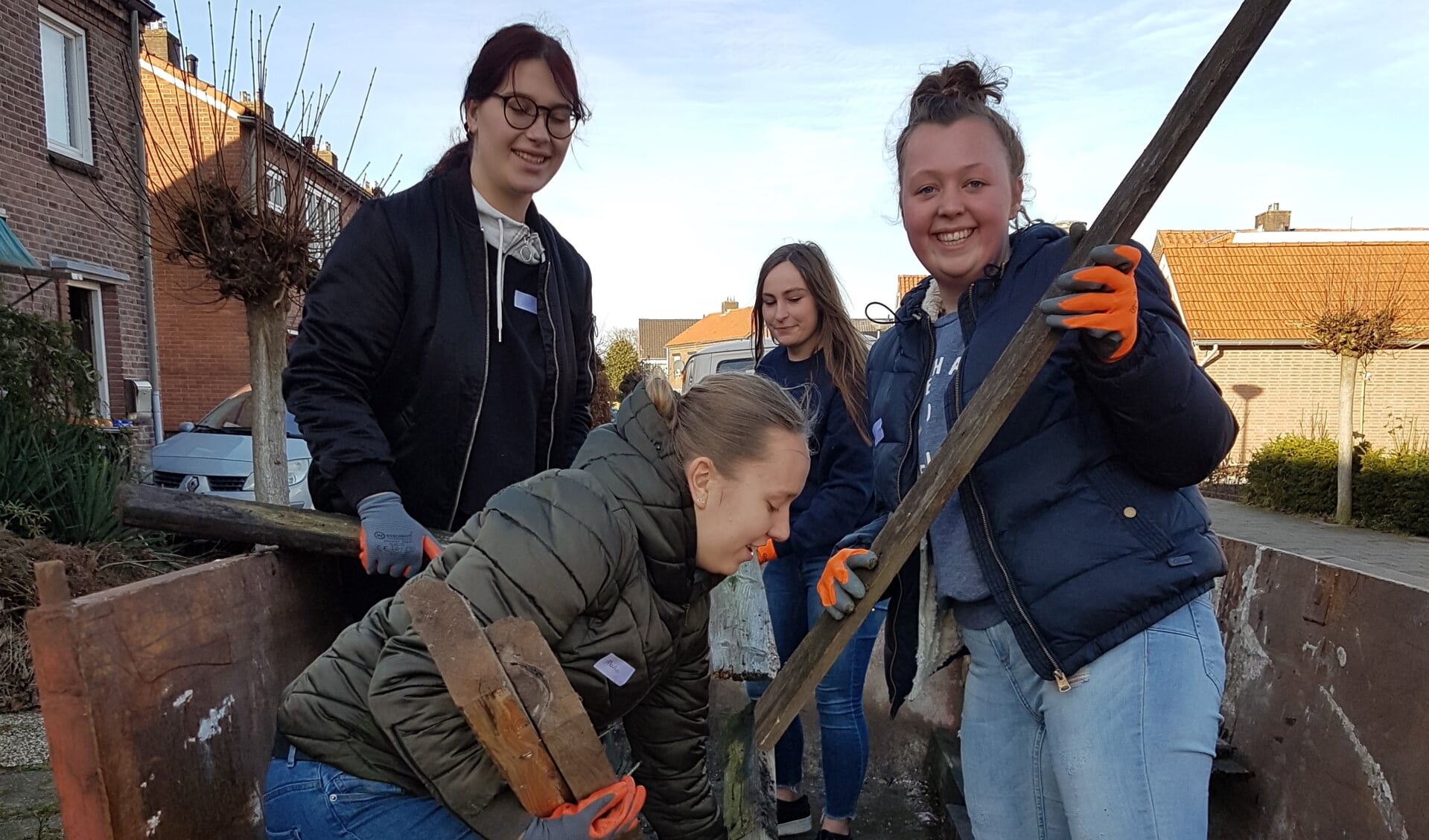 Vier studenten vullen een van de containers met grof vuil uit de achtertuin. Foto: Present Winterswijk