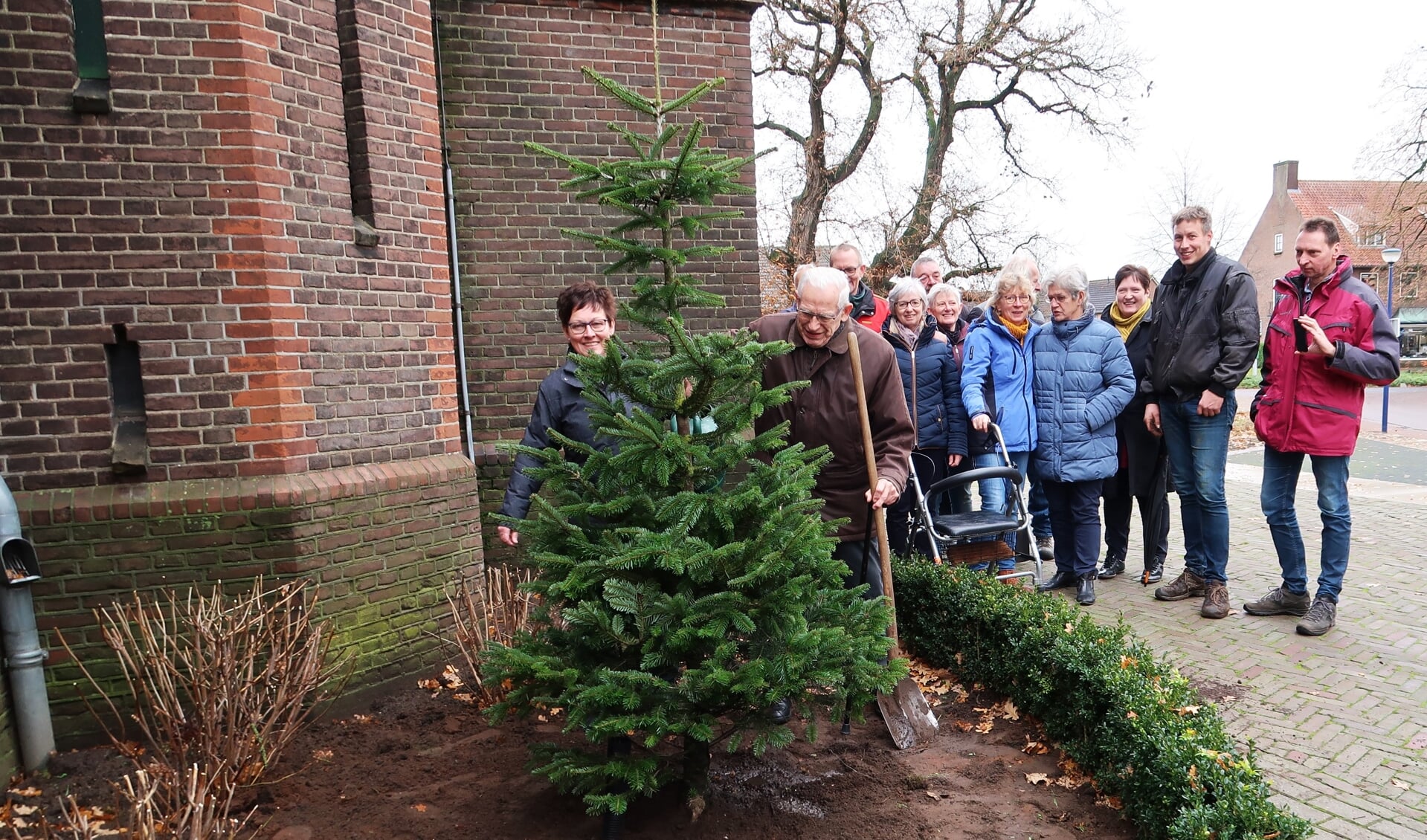 Pastor Hendrik Scholten en Ida Schilderinck planten de nieuwe (kerstboom)spar van Kiddoesj. 