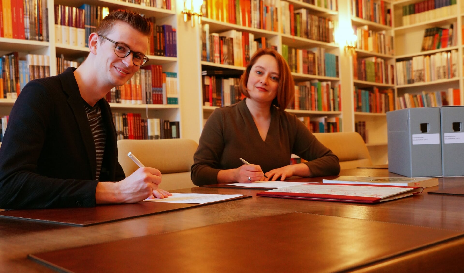 Wethouder Mathijs ten Broeke en uitgever Winnie Urban ondertekenen overdracht archief WalburgPers naar RAZ. Foto: PR