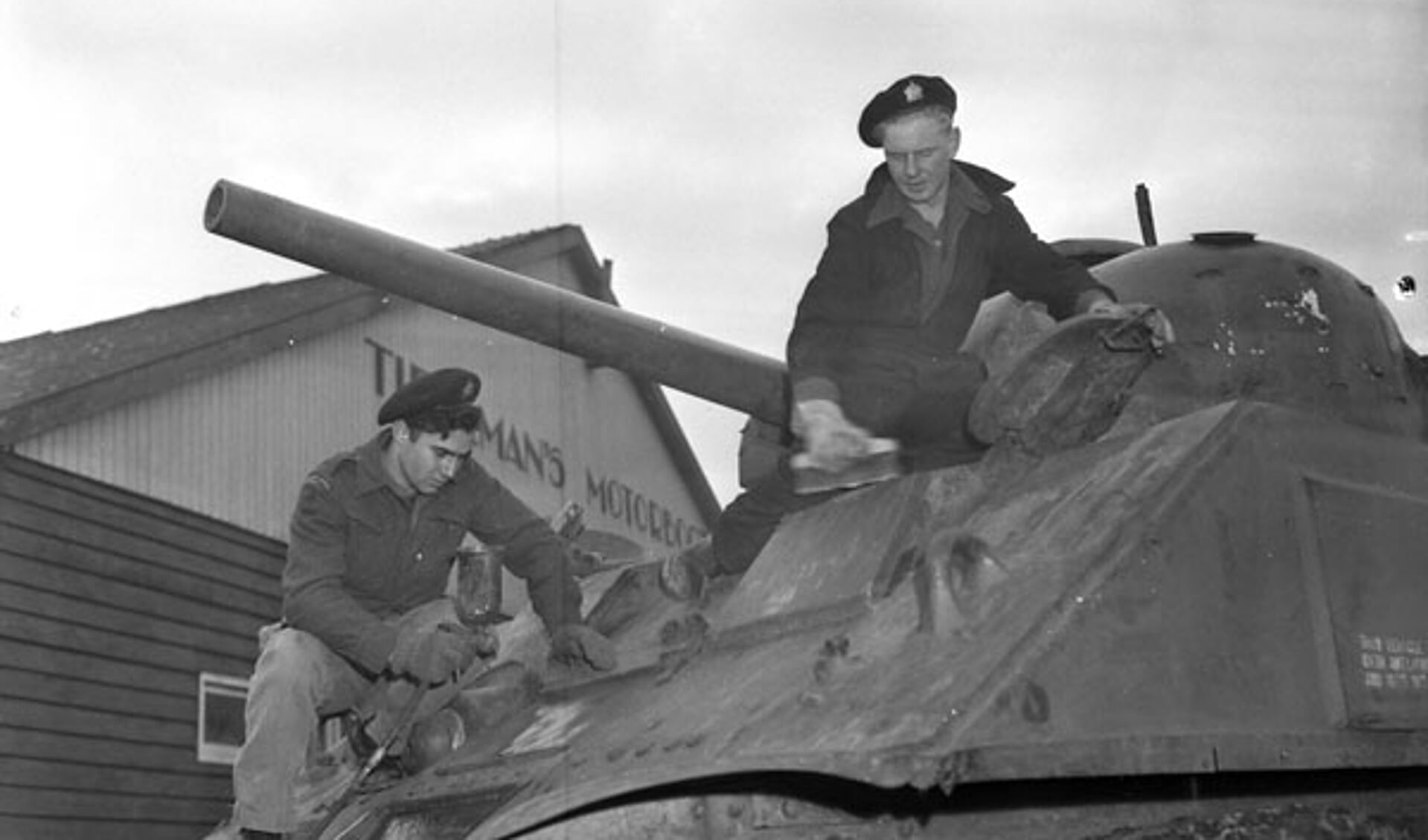 Soldaten poetsen de Sherman M4A4 tank, voor de werkplaats van Tieleman op 22 november 1945. Deze tank staat nu aan de Torontostraat in Doetinchem (Foto: Collectionscanada)