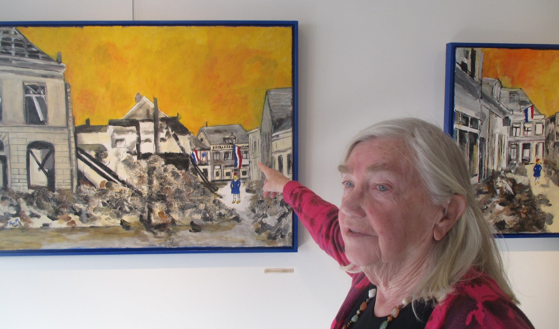 Ans van As-Berendsen voor een van haar schilderijen, wijzend naar haar ouderlijk huis in de Boliestraat. Foto: PR