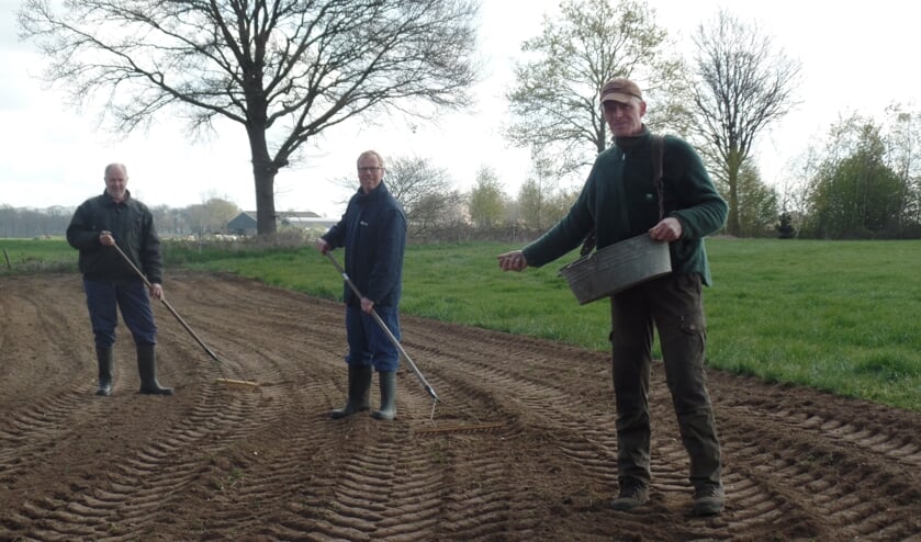Erwin Dijkman zaait het 'zomergloed' langs een van de weilanden in 't Zwiepse Broek. Jan Dinkelman en Henk van Bindsbergen harken het zaadmengsel in. Foto: Jan Hendriksen,