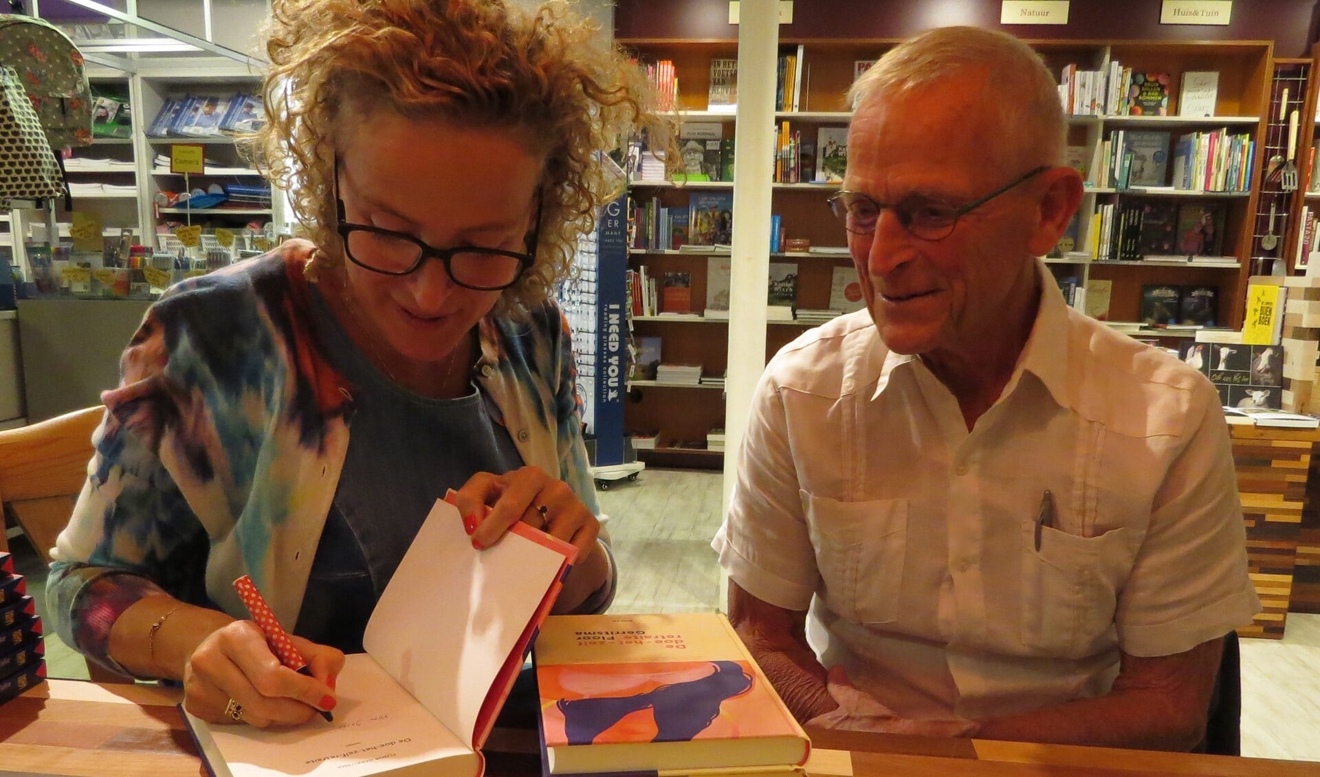 Floor Gerritsma signeert, met vader Piet Hein Gerritsma aan haar zijde, haar debuutroman. Foto: Josée Gruwel