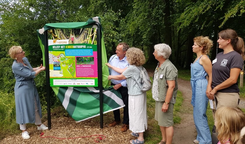 Burgemeester Marianne Besselink, Frans Helmich en Annemieke van der Velden onthullen samen het informatiebord van het kindernatuurpad en het trimparcours. De andere IVN natuurgidsen Karin van Heijst, Marleen Raats en Tilda Groenhof kijken toe. Foto: Alice Rouwhorst