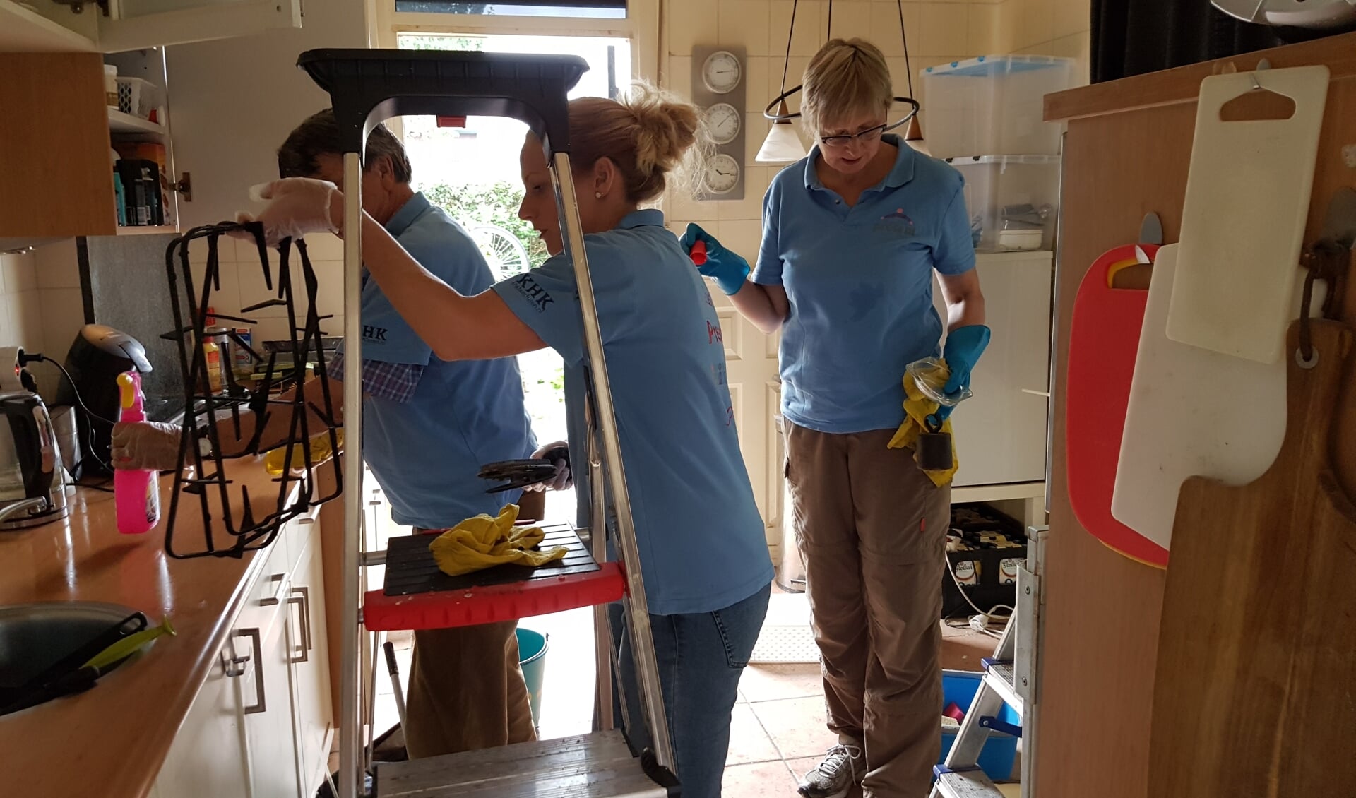 Drie vrijwilligers ruimen de keuken op en maken alles schoon