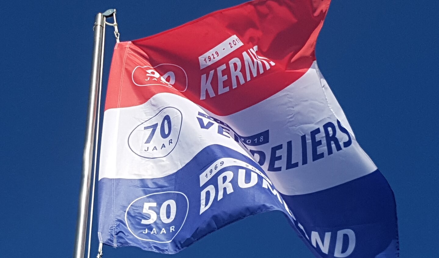 De speciaal ontworpen jubileumvlag wappert boven het kermisterrein in Lievelde. 