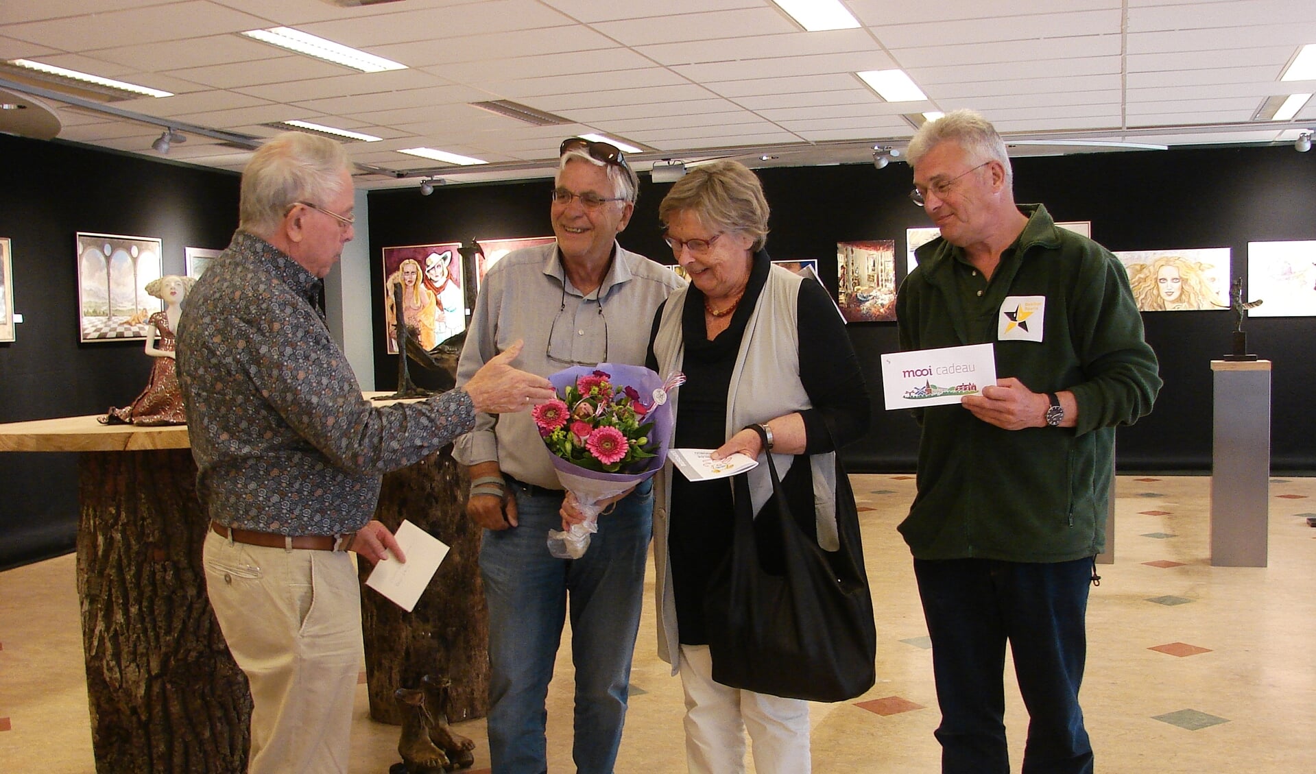 Joop Huisman verrast het echtpaar Cremer uit Haren (Groningen) met een mooi boeket bloemen en een tegoedbon voor een lunch bij lunchroom Lievestro. Wim Slotboom overhandigt namens de VVV een bon van de Stichting Mooi in Ruurlo. Foto: PR. 