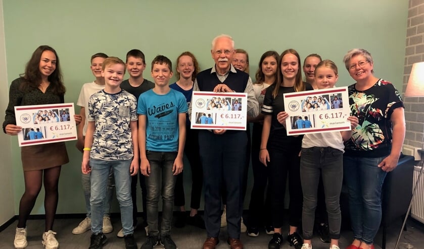 Pater Ton Bun krijgt uit handen van een aantal leerlingen een mooie cheque overhandigd. Foto: PR