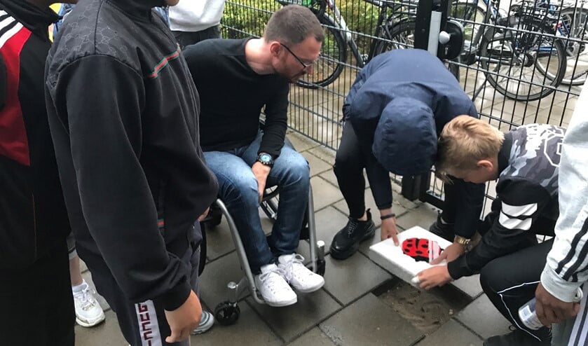 Jongeren leggen een tegel met een lieveheersbeestje, als symbool tegen zinloos geweld. Burgemeester Otwin van Dijk kijkt toe. Foto: PR