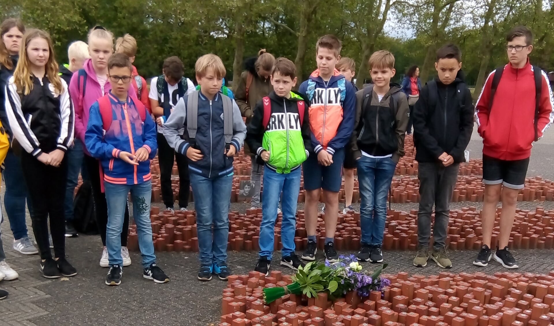 Als afsluiting van het Westerbork Scholenproject bezoeken de leerlingen Kamp Westerbork. Ze besluiten deze excursie met het gezamenlijk leggen van een bloemstuk bij het monument op het kampterrein. Foto: PR. 