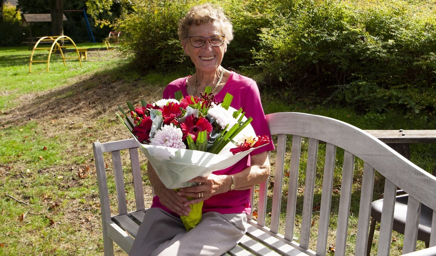 Gerda Ponds krijgt een mooie bos bloemen én een bankje voor in haar eigen tuin. Foto: PR speeltuin De Schatberg