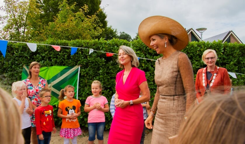 Gastvrouw Ineke Dezentjé, koningin Máxima en burgemeester Marianne Besselink lopen over het schoolplein van basisschool De Rank tussen de zingende kinderen door. Foto: Liesbeth Spaansen