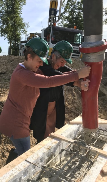 Toekomstig bewoner Ilona stort samen met bestuurder Irma Harmelink het eerste beton voor de nieuwe woning. Foto: PR