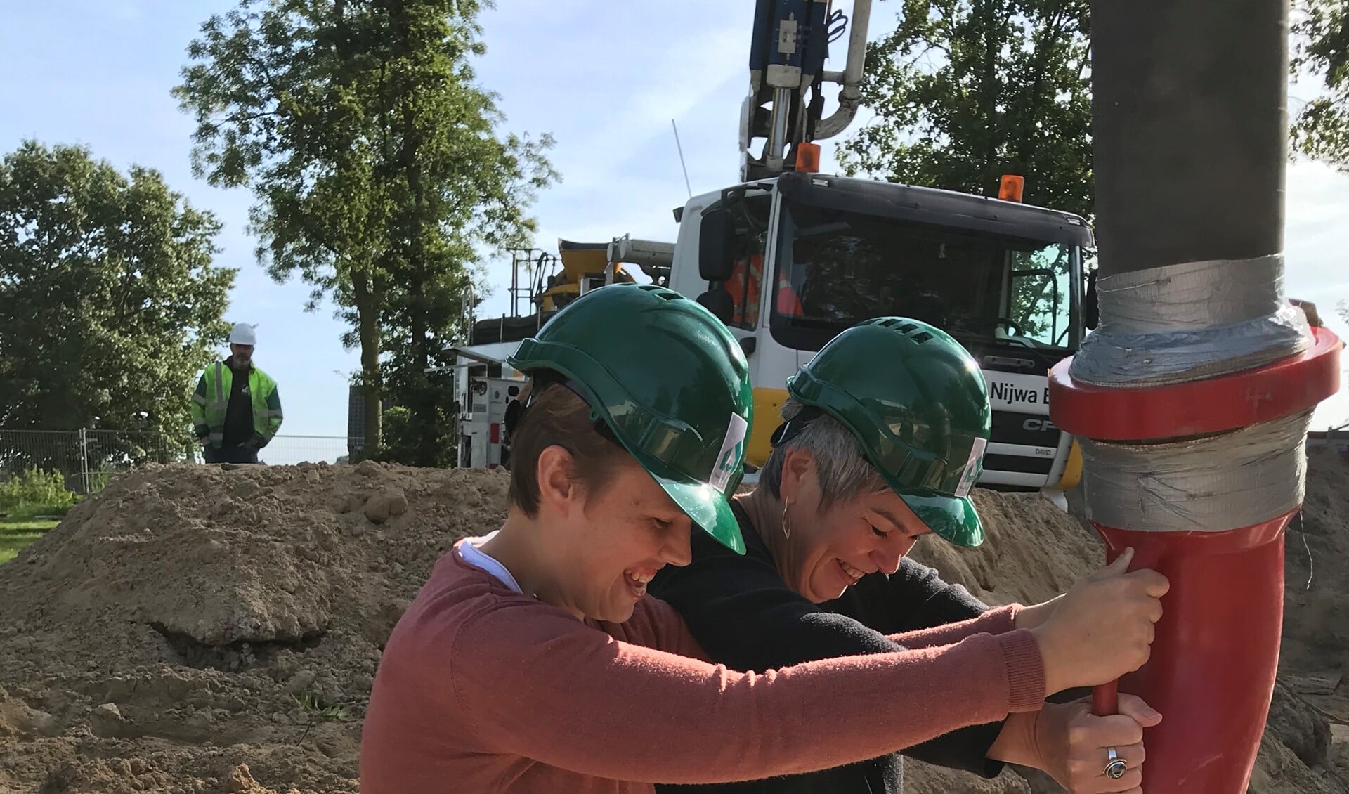 Toekomstig bewoner Ilona stort samen met bestuurder Irma Harmelink het eerste beton voor de nieuwe woning. Foto: PR