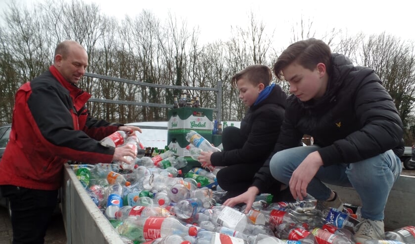 Ard, Dennis en Jacco Kettelerij bij hun ingezamelde 'berg' lege flessen en kratten bier. Foto: Jan Hendriksen.