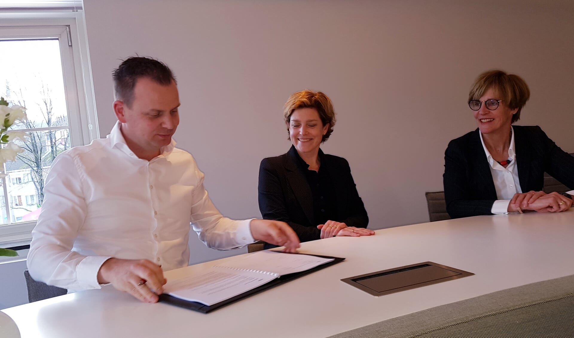 Bart Wopereis gaat het contract tekenen, naast hem Marjolein Wenting en daarnaast burgemeester Bronsvoort. 