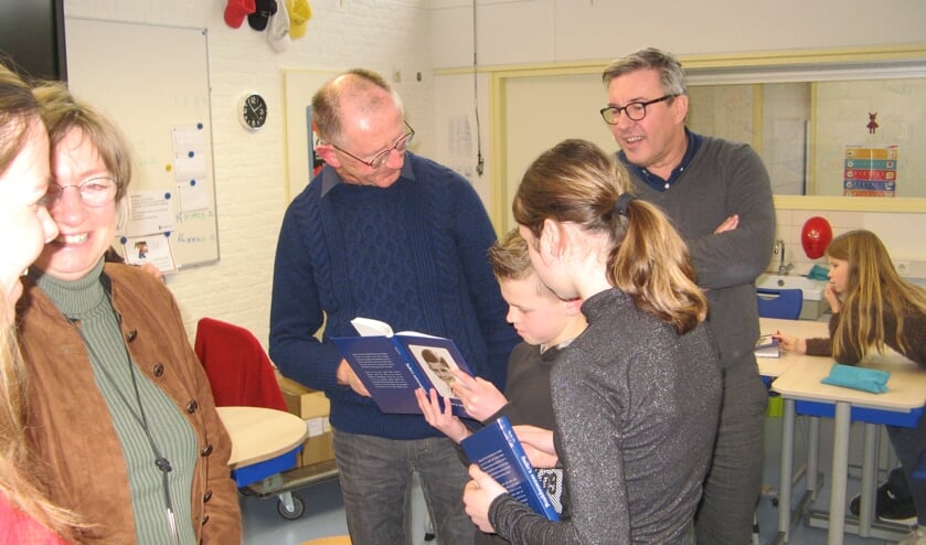 Henk Vis en Jan van der Horst met twee leerlingen die het boekje Sallo's ontsnapping bekijken. Foto: Bart Kraan