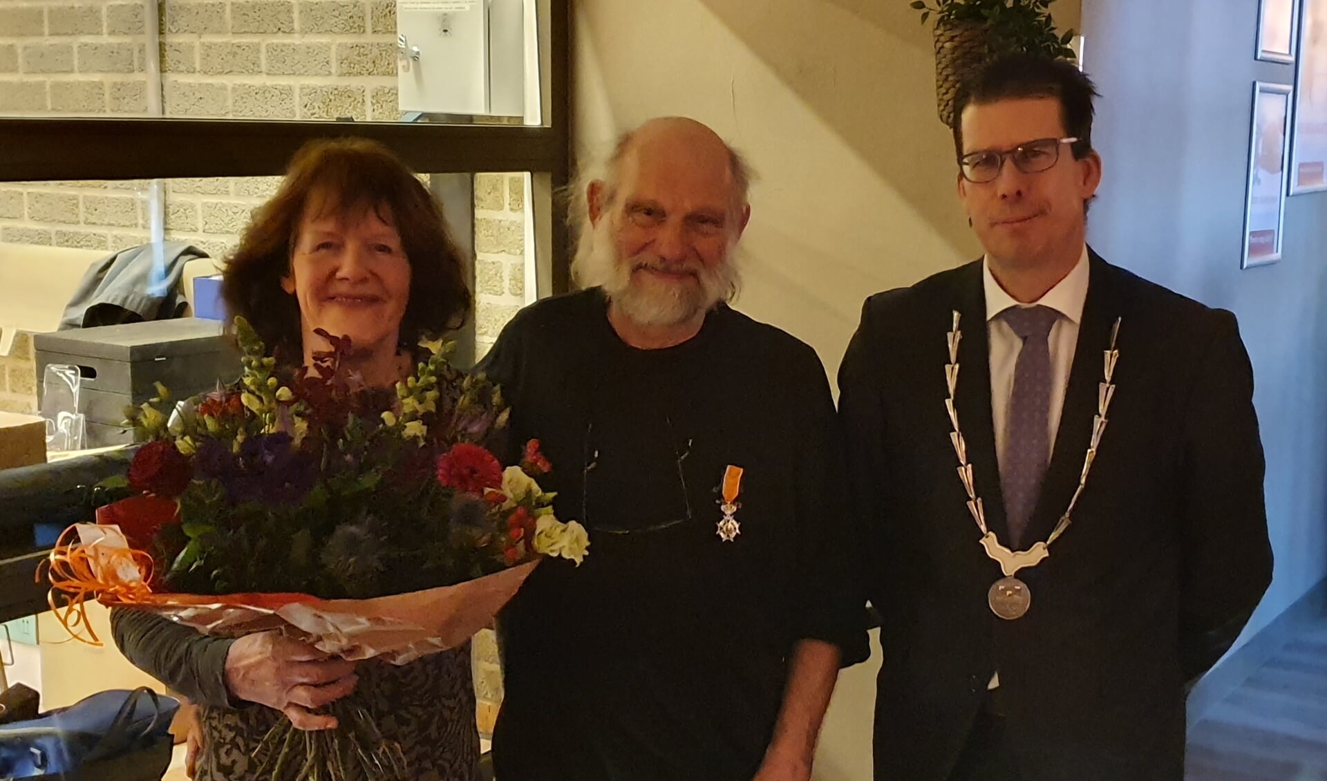 Jan en Ria Krooshof met lintje en bloemen naast burgemeester Joost van Oostrum. Foto: Rob Weeber