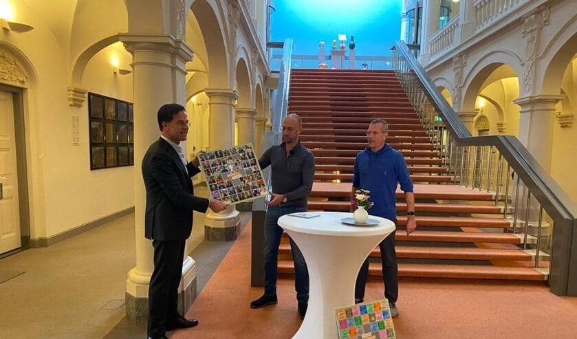 Bert van Zijtveld en Alain Schepers overhandigen het bord aan premier Mark Rutte. Foto: Algemene Zaken