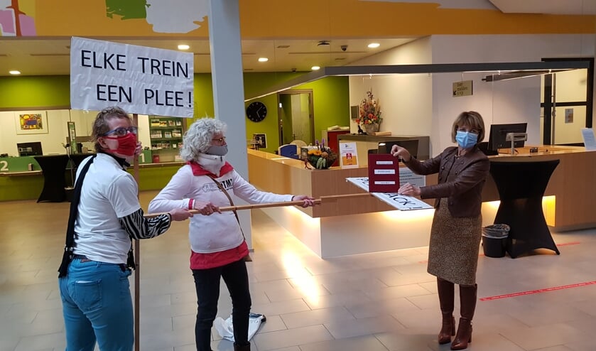 <p>Sandra Gosseling (l) en Greetje van Amstel bieden wethouder Zomer een boek vol handtekeningen aan: ‘Elke trein een plee.’ Foto: Han van de Laar </p>