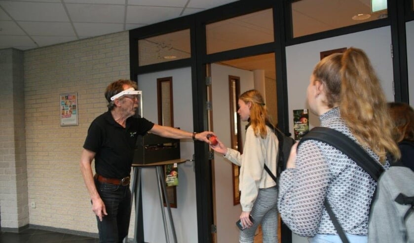 <p>Conciërge Henry Hummelink deelt LTO appels uit op het Marianum Lichtenvoorde</p>