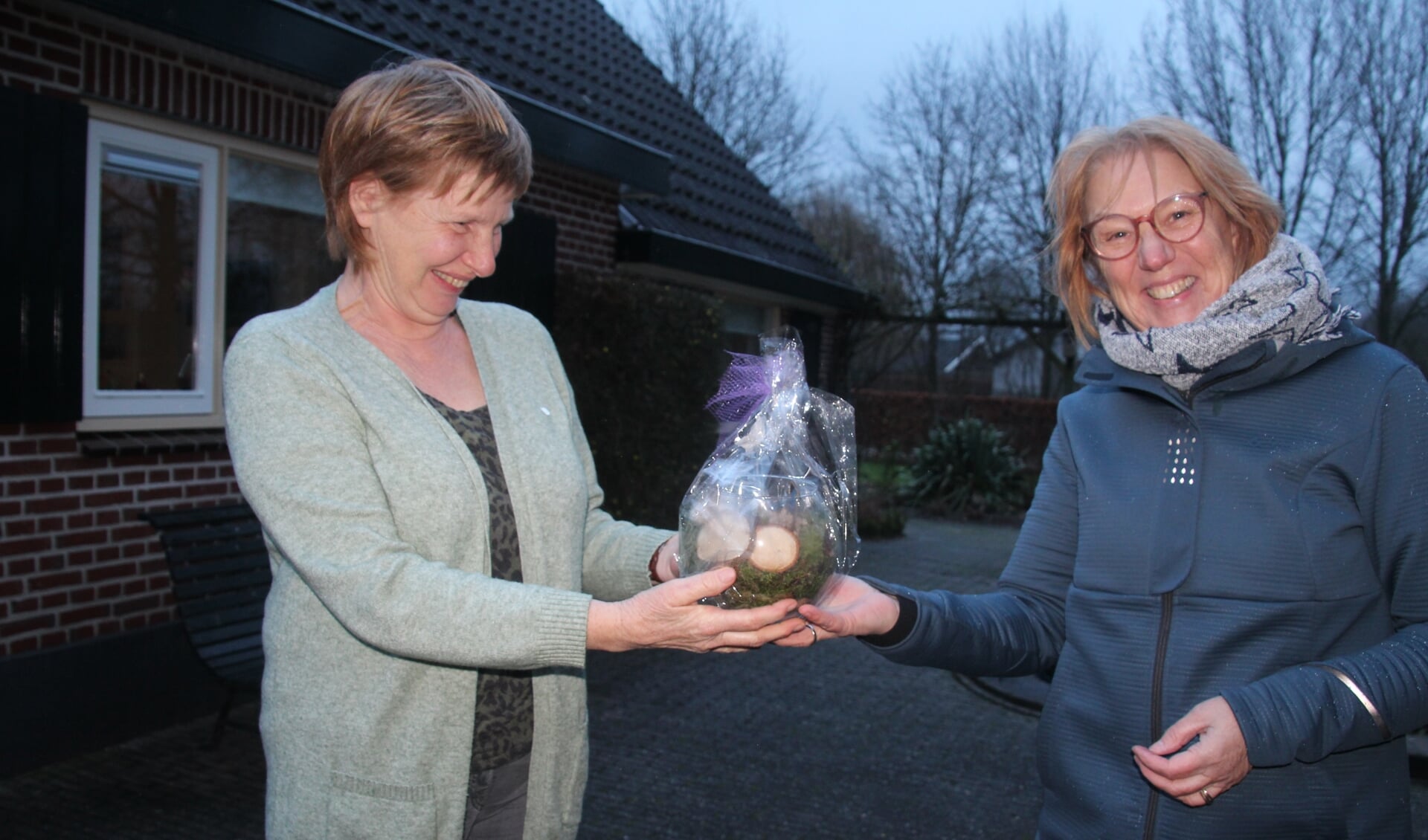 Hanny Sesink (links) krijgt van Leida van Egteren de insigne, de oorkonde, een bloemstukje en een cadeaubon. Foto: Joop Groot Roessink