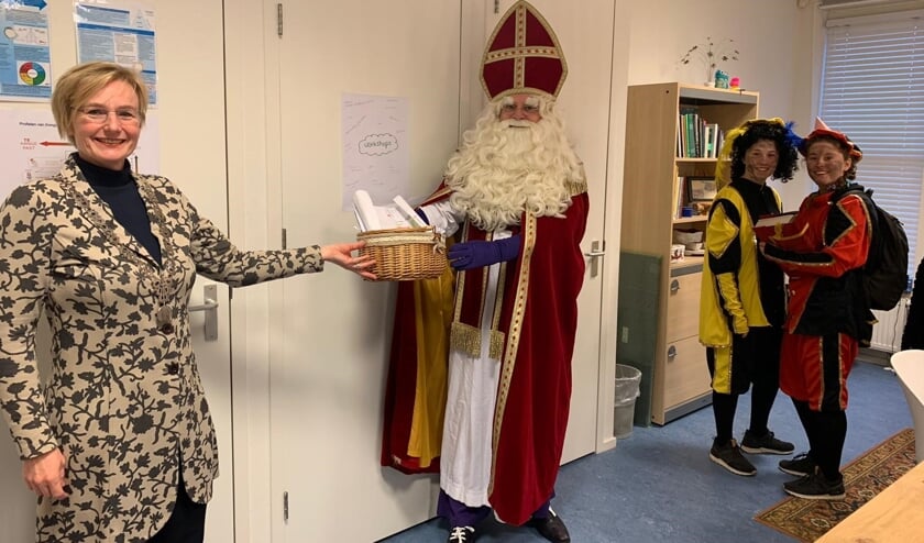 <p>Marianne Besselink overhandigt de Sint een mand vol tekeningen. Foto: PR/Dorpsschool Vorden</p>