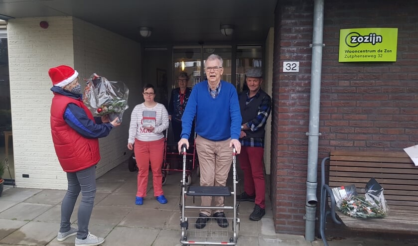 <p>Irene Burger, voorzitter van de kerstcommissie, overhandigt een kerstboeket aan de bewoners van Zozijn (locatie De Zon). Foto: Karin Krijt-Garritsen</p>
