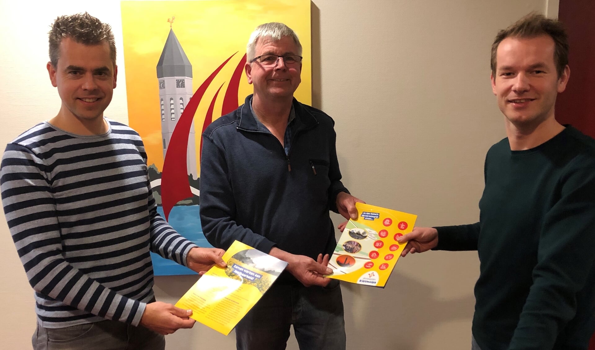 Joost Lansink (rechts), projectgroeplid 'Dorpsplan Rietmolen', overhandigt het nieuwe dorpsplan aan Vincent Lansink. Die geeft het door aan Patriek Piepers (links). Foto: Anja van Maren