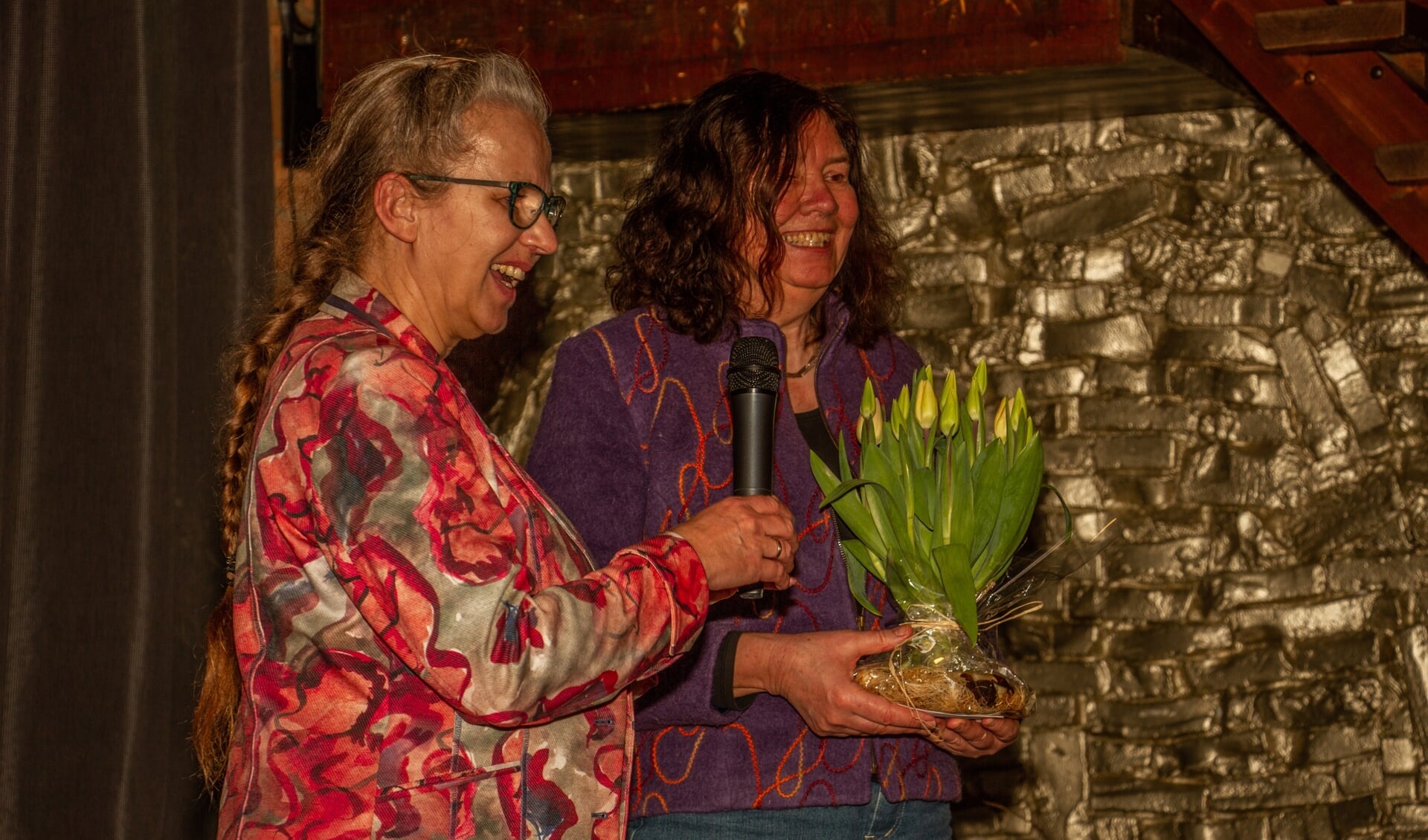 Schrijfster Alice Garritsen krijgt van Alien Maalderink een schoof tulpen. Foto: Liesbeth Spaansen