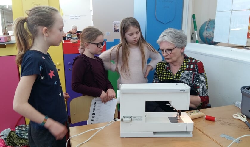 Gerrie de Reuver vertelt Fien, Sytske en Jikke over kledingreparatie. Foto: Hester Tolman
