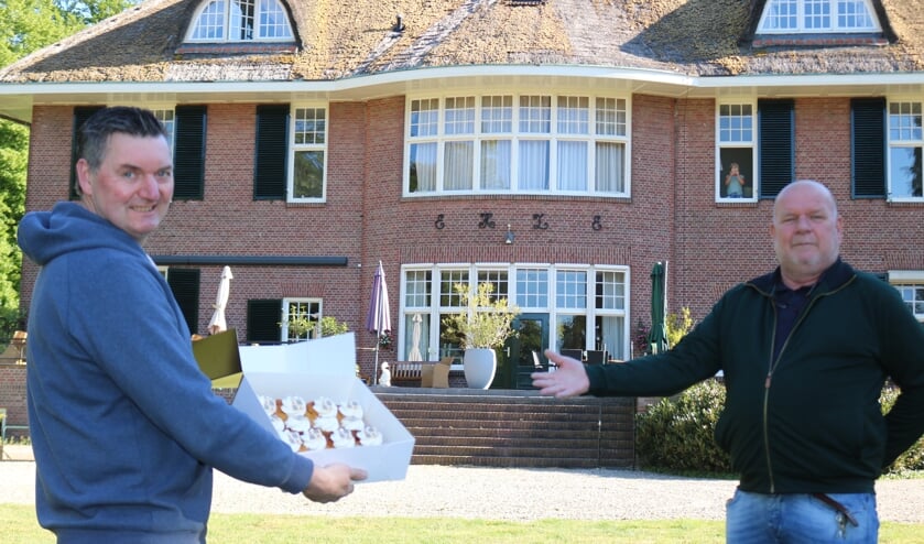 Bakker Wijnand Stegeman biedt zorgdirecteur Henk Boelen (rechts) de doos met gebak aan. Foto: Arjen Dieperink