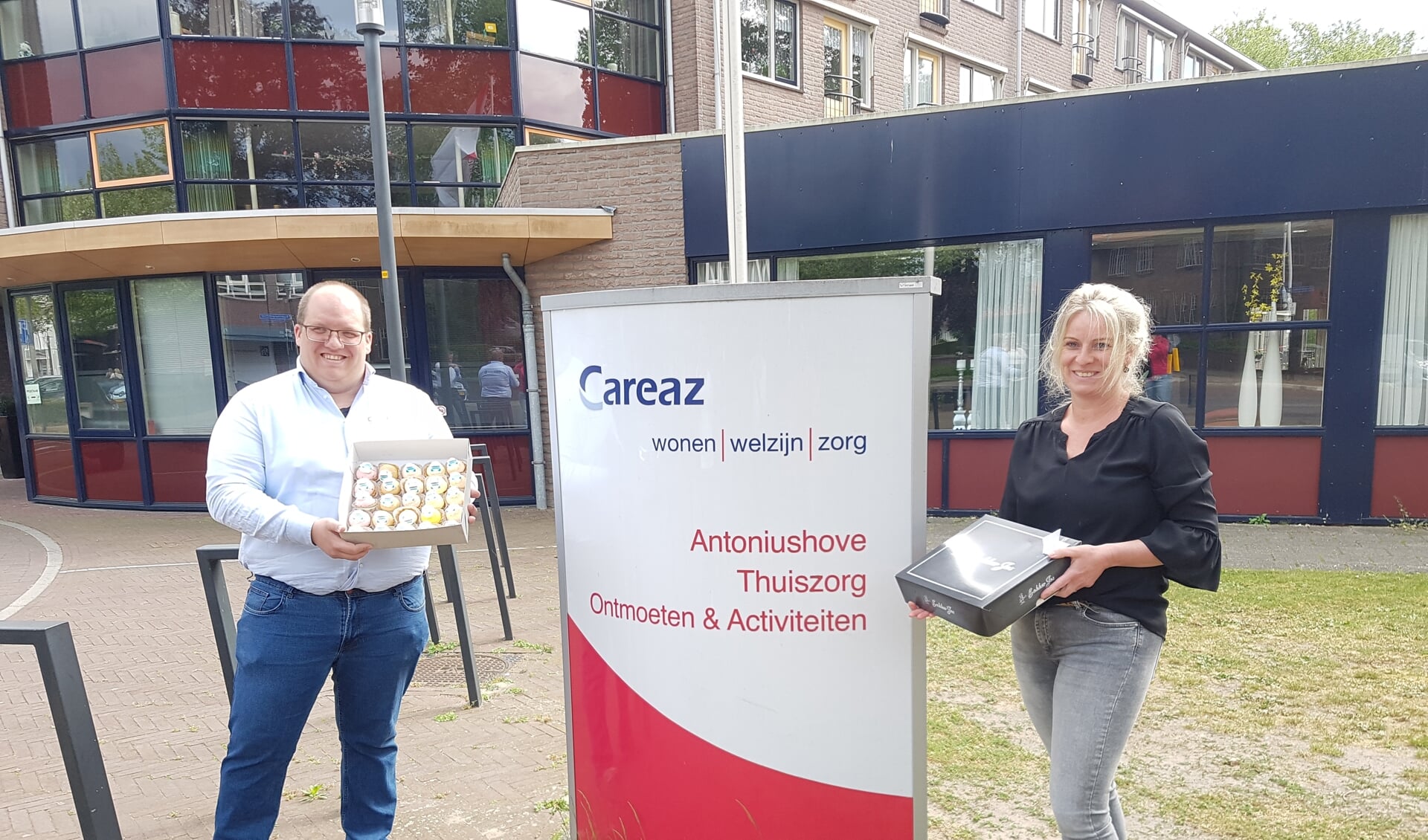 Geert-Jan Scholtz, bedrijfsleider Obbink Lichtenvoorde, en Manon Huinink, welzijnscoach Careaz, met twee dozen gebakjes voor de bewoners van de Antoniushove in Lichtenvoorde. 