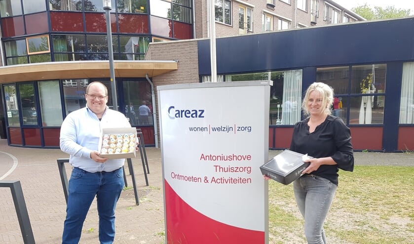 Geert-Jan Scholtz, bedrijfsleider Obbink Lichtenvoorde, en Manon Huinink, welzijnscoach Careaz, met twee dozen gebakjes voor de bewoners van de Antoniushove in Lichtenvoorde.