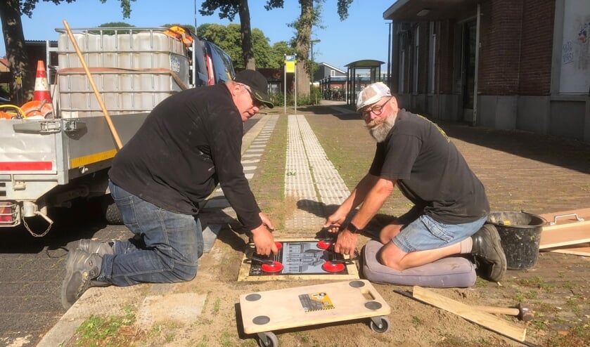 Een tegel wordt gelegd door Frank Sessink (l) en Harry Jansen. Foto: Stichting Tegelroute Bronckhorst