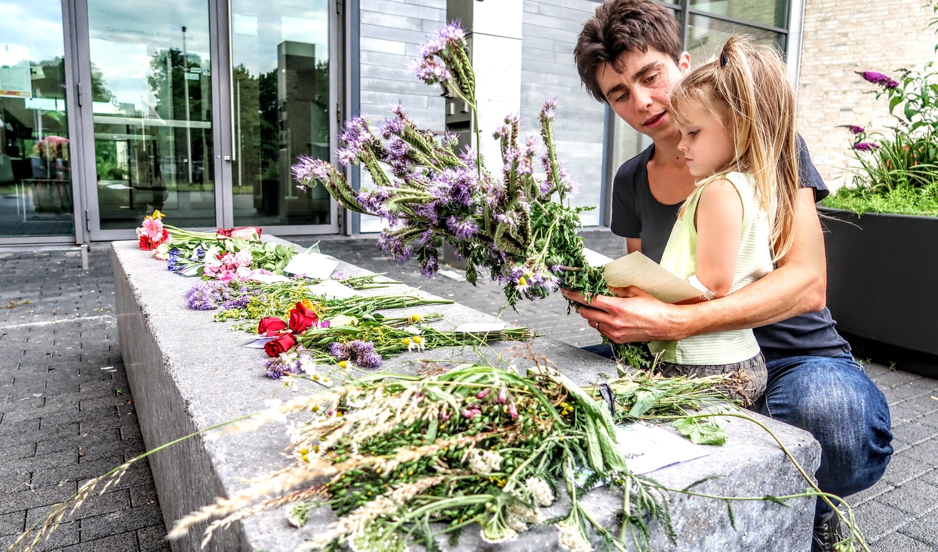 Maaike Kuyk uit Vorden kwam zondag samen met haar dochtertje Elaine naar het gemeentehuis van Bronckhorst in Hengelo om met bloemen haar stem tegen de coronamaatregelen te laten horen. Foto: Luuk Stam