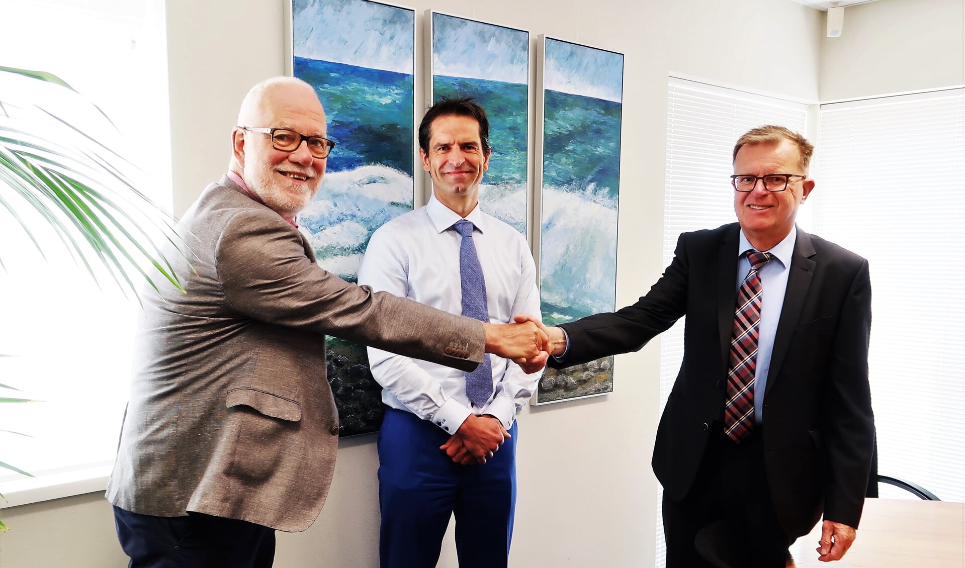 Hans Scheinck (rechts) en Harry Paf (links) feliciteren elkaar met de officieel beklonken fusie. In het midden notaris Edwin Roerdink. Foto: Theo Huijskes
