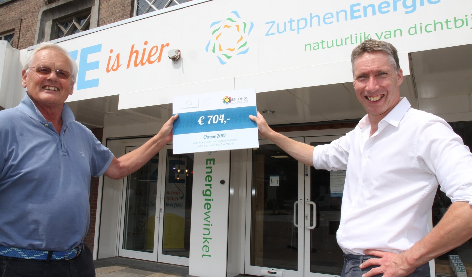 Wouter van de Wall Bake van ZutphenEnergie overhandigt een cheque van 704 euro aan Jan van Breda van het Torenfonds. Foto: PR