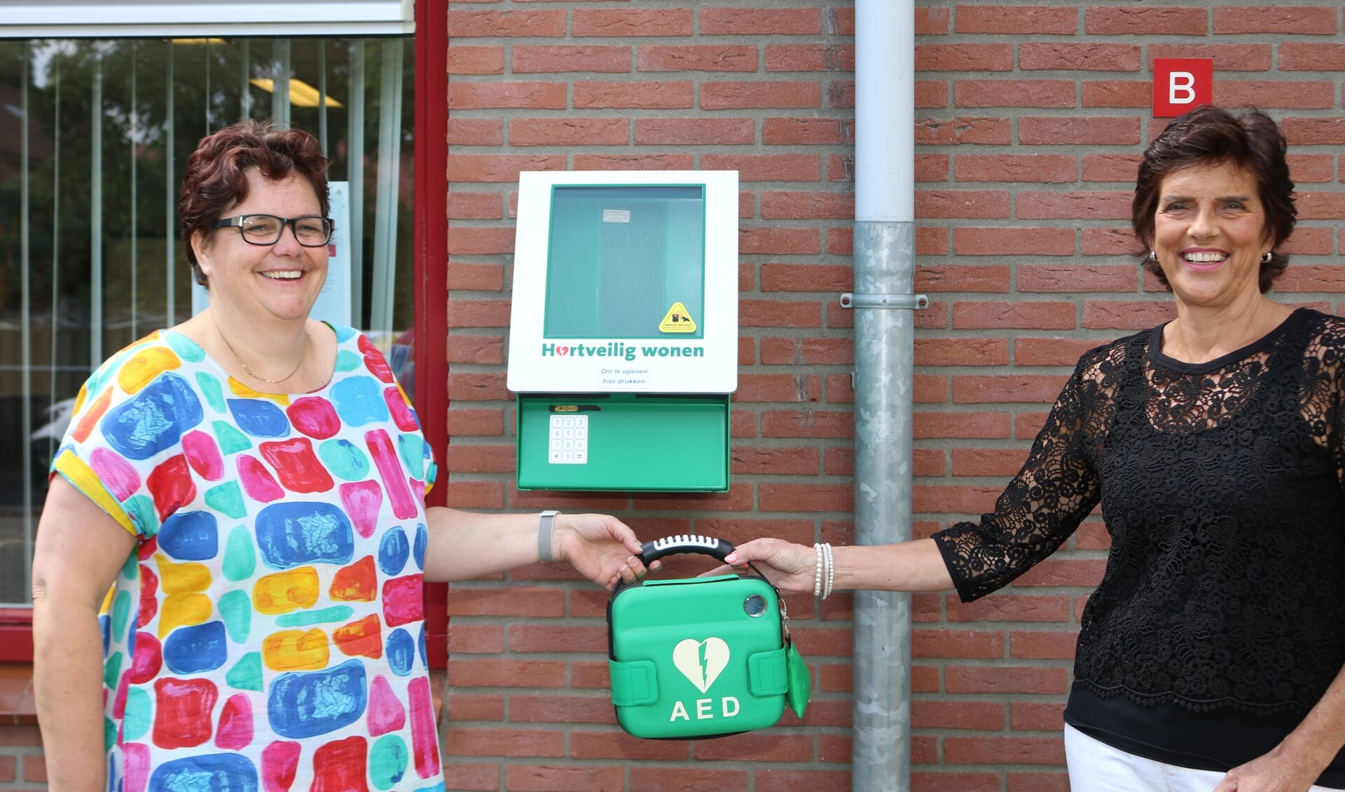 Apotheker Miranda Koopal (l) overhandigde de AED aan Marianne Hebbink, directeur De Rank. Foto: Arjen Dieperink