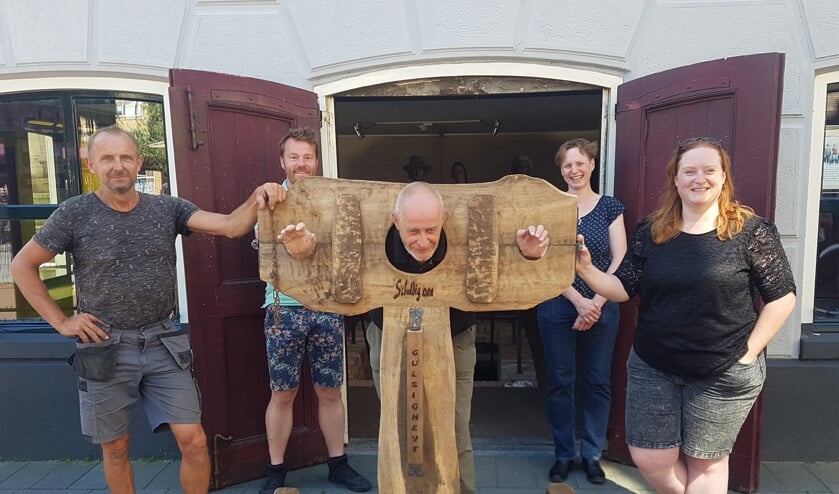 Gerard van Huet is aan de schandpaal genageld. Verder vlnr Frank Diekman, Michael Lammers van Escaperoom, Sandra Zieverink van de VVV en Joske Elsinghorst van de Werkgroep Promotie Groenlo. Foto: Kyra Broshuis