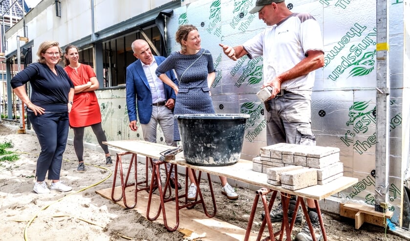 Een vakman geeft huisartsen Petra Gerritsen, Sabine Janssen en Gerjo Steeneveld (v.l.n.r.) en fysiotherapeut Ton van Walstijn (derde van links) uitleg over het metselen. Foto: Luuk Stam