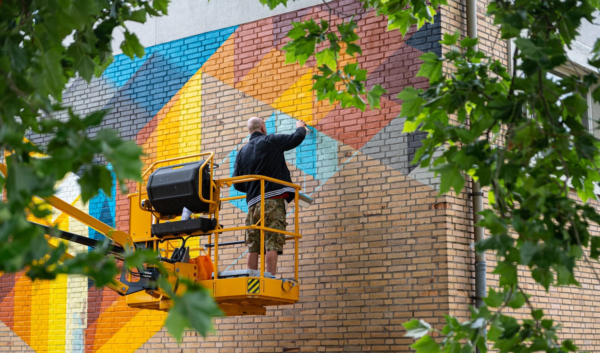 De street art artist Mr. June werkt aan zijn kunstwerk op de muur van de 'stenen gymzaal'. Foto: Rick Mellink