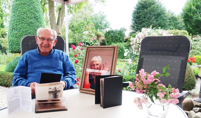 Tonnie te Plate, zittende in zijn eigen fraaie achtertuin met naast hem de foto van vrouwlief Riek. Foto: Theo Huijskes