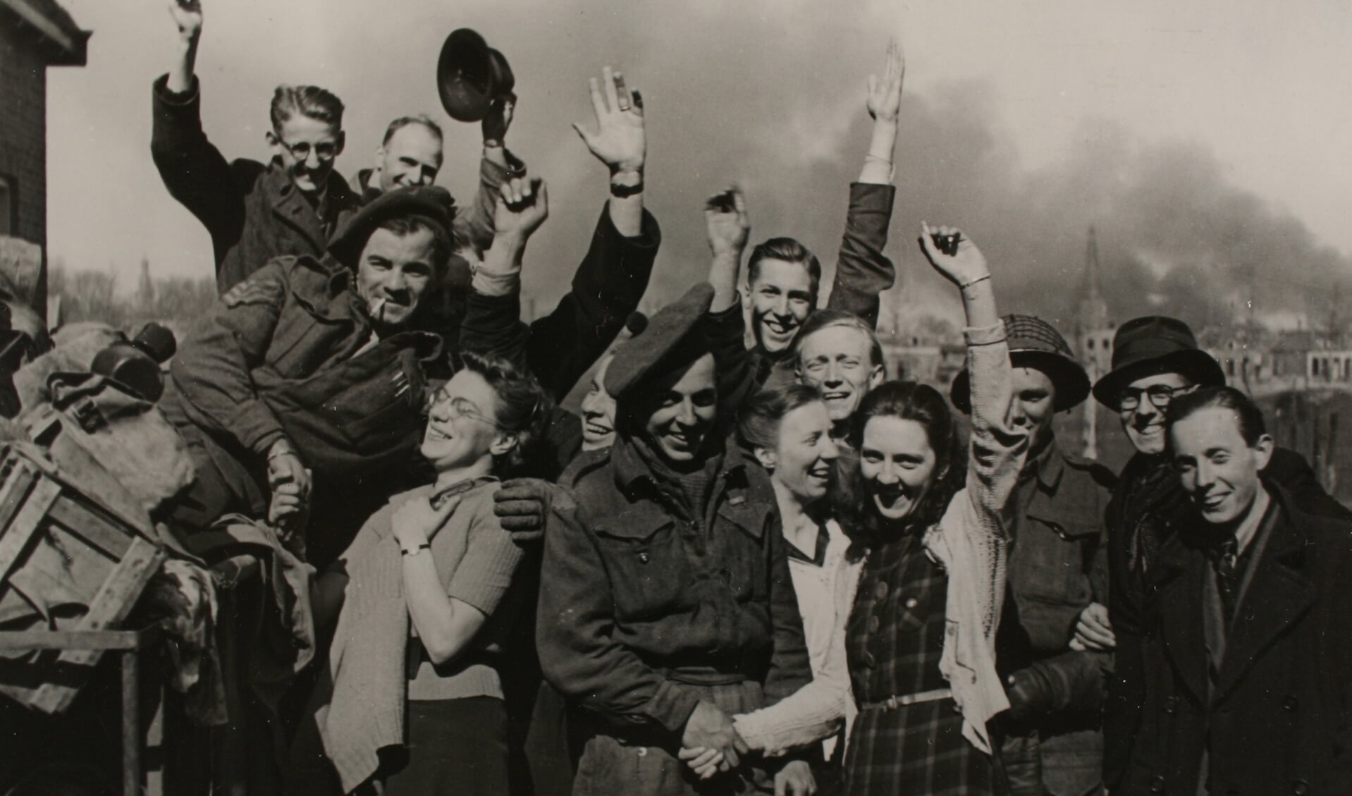 Zutphen na de bevrijding in 1945: een groep feestende burgers rond enkele Candadese militairen met op de achtergrond de brandende Nieuwstad met de St. Jan. Foto: Stedelijk Museum Zutphen