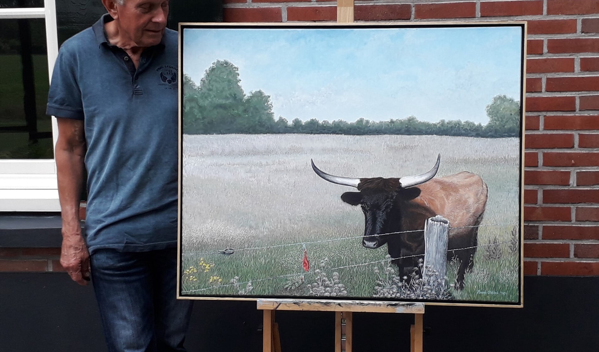 Bram Obbink met een schilderij van een nieuwsgierige koe in het Wooldse Veen. Foto: Obbink