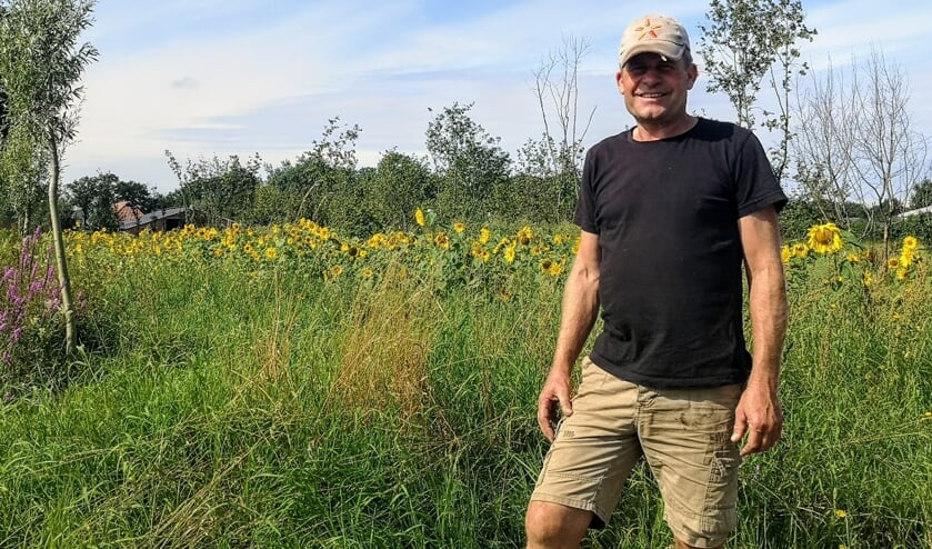 René Lubberdink bij het perceel met hazelnootbomen, dat achter de zonnebloemen zichtbaar is. Foto: Henri Bruntink
