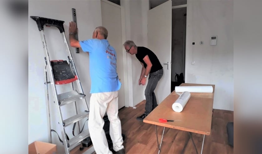 Leo en Gerrit zijn bezig met de voorbereiding voor het behangen