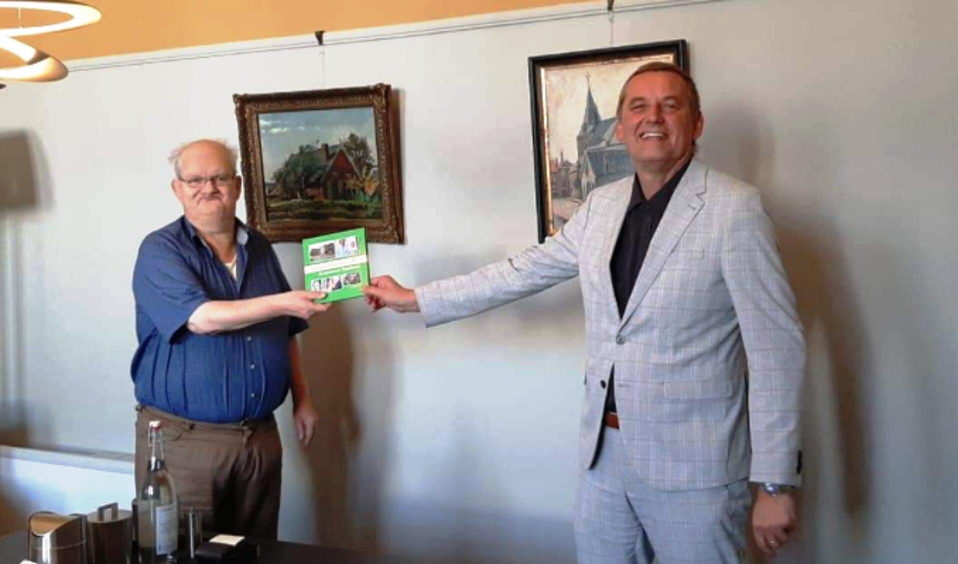 Leo van der Linde overhandigt het burgemeestersboek aan Anton Stapelkam. Foto: Communicatie gemeente Aalten
