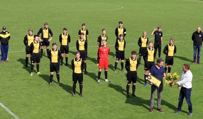 Herman Vrielink overhandigt bloemen en een ingelijst shirt aan Rob Lucassen. Foto: PR