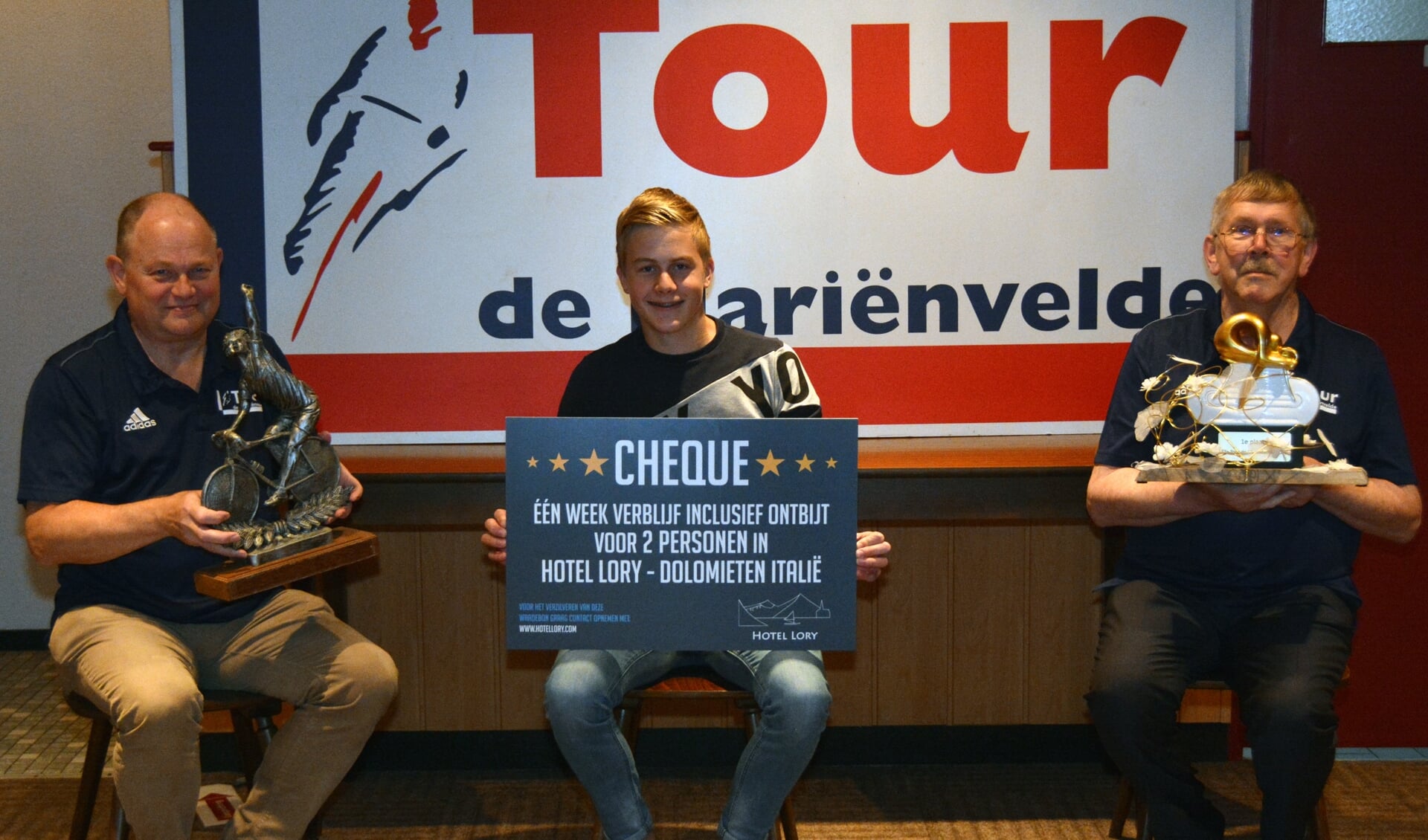 De 16-jarige winnaar Tjibbe de Boer uit Aalten zit met de cheque voor de eerste prijs tussen twee directieleden van de Tour de Marienvelde, Henny Heutinck (rechts) en Henri Weikamp (links). Foto: PR